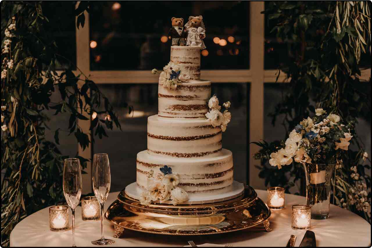 Wedding cake on a table, showcasing a sophisticated design with gold accents and floral decorations.